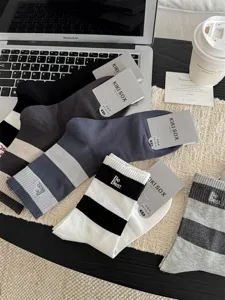 Nahaufnahme gestreifter Baumwoll-Herrensocken mit gesticktem Logo und elastischem Bund.