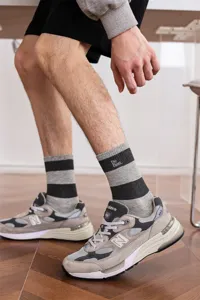 Detailaufnahme gestreifter Herrensocken mit Buchstabenbestickung und elastischem Bund.