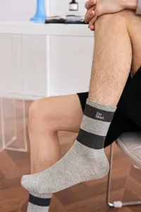 Detailaufnahme von Freizeitsocken für Herren mit Streifen, Stickerei und geripptem Bündchen.