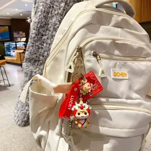 Witte rugzak met schattige cartoon leeuw pop sleutelhanger, stijlvolle casual dagelijkse tas voor dames.