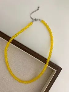 Primo piano della collana di perle gialle, fini perle di pietra rotonda con catena in metallo.