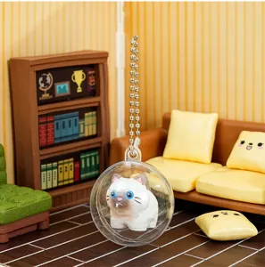Close-up of a cute cat figurine inside a clear capsule keychain, miniature background.