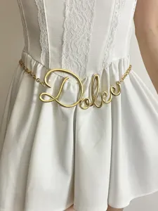 Dettaglio catena da cintura in metallo dorato con raffinato design corsivo per abiti.
