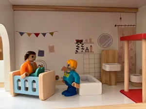 Vista dettagliata della casa delle bambole in legno con statuine, lettino e mobili da bagno.