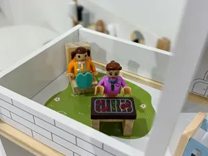 Dettaglio del set in miniatura della casa delle bambole in legno con figurine.