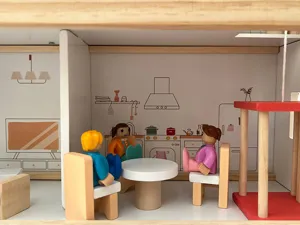 Dettaglio interno della casa delle bambole in legno nordico con personaggi e mobili.