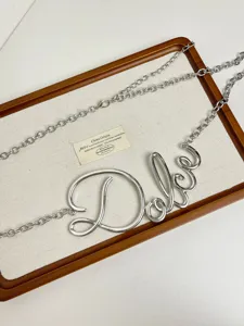 Vista dettagliata della catena in metallo argentato, design corsivo creativo per accessorio.