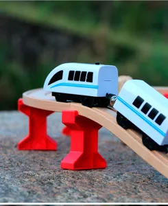 Detail shot of electric high-speed train toy running on wooden track bridge outdoors.