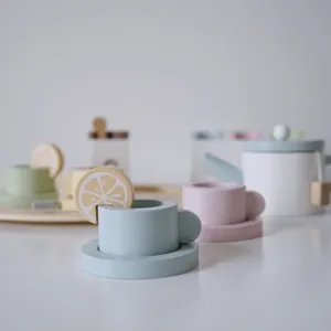 Close-up detail of wooden afternoon tea toy set featuring cute pastel cups and lemon slice.