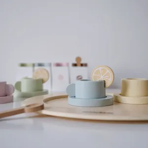 Detailed closeup of pastel wooden tea cup toys, lemon decor, and tray for kids play kitchen.