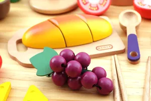 Wooden play kitchen food toy cutting set detail view featuring wooden bread and grapes.