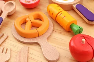 Wooden pretend play toy set detail showing cuttable vegetable and fruit models on a board.
