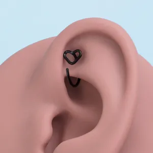 Nahaufnahme von schwarzem Herz Piercing Schmuck auf Ohrmodell, minimalistischer Stil.