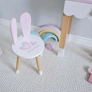 Vue de détail d'une jolie chaise d'enfant en bois avec des oreilles de lapin, rose et blanc.