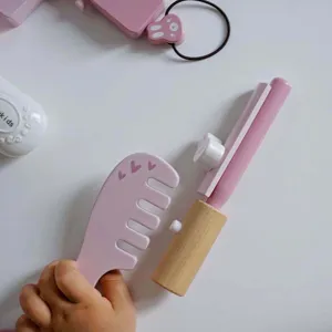 Vue détaillée de jouet de maquillage en bois, peigne rose et outil de coiffure pour enfants.