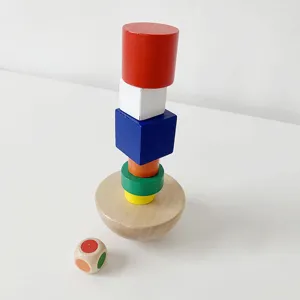 Wooden stacking balance game detail, colorful blocks and small dice on white base.