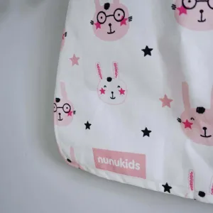 Vue détaillée du tissu du sac de rangement de jouets avec motif de lapin mignon et logo.