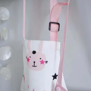 Gros plan d'un sac de rangement suspendu blanc avec des lanières roses et un motif de lapin.