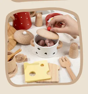 Wooden kitchen toy detail shot showing miniature pot, cheese, and utensils for play.