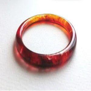 Red translucent resin bangle detail closeup, glossy finish handmade jewelry accessory piece.