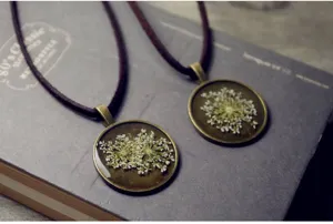 Close-up of vintage bronze round dried flower resin pendant necklace detail view