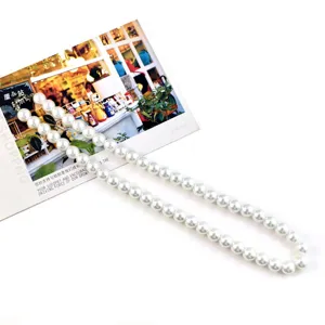 Witte parelketting detail, lange decoratieve ketting, tasriem en DIY knutselaccessoire.