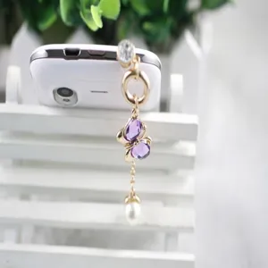 Kristalen vlinder telefoon stofplug detail met parel hanger, elegant accessoire design.