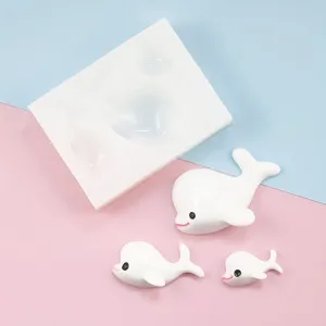 Detail view of cute dolphin silicone mold and miniature white dolphin figurines for DIY crafts.