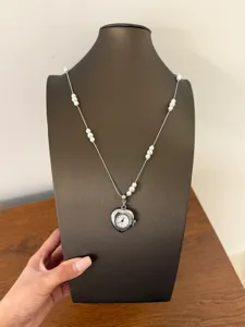 Close-up detail shot of the heart-shaped watch pendant necklace with pearl beads on chain.