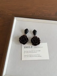 Close-up detail shot of dark brown rose earrings featuring wooden and resin geometric design.