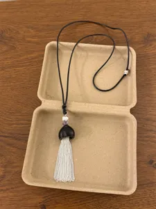 Close-up of a new Chinese style black tassel necklace with silver chain details and beads inside a box