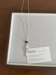 Collana con ciondolo a scheletro di pesce argentato con perle nere per stile da donna.