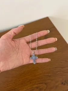 Silver cross pendant necklace featuring sparkling blue zirconia stones on a delicate chain.
