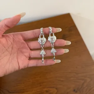 Silver heart lock and key rhinestone drop earrings detail shot, elegant fashion jewelry.