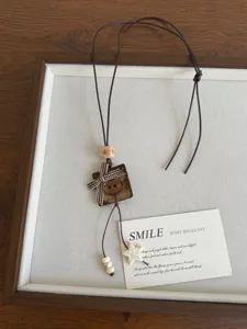 Detail view of the retro coconut shell cat necklace with wooden beads and cute plaid bow.