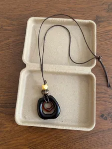 Close-up detail of the vintage ethnic style pendant necklace with adjustable brown cord and beads.