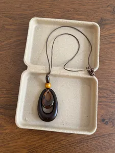 Close-up detail of the retro wooden beaded necklace with geometric pendant in a simple box.