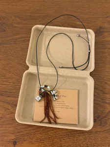 Detailed view of vintage bohemian style beaded necklace with charms and paper box packaging.