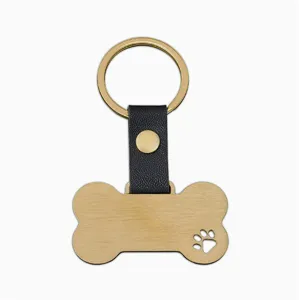 Detail en gros plan du porte-cles pendentif pour animal en forme d'os dore et cuir noir.