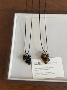 Close-up of natural stone grape beaded necklaces on dark cords, elegant autumn sweater chain.