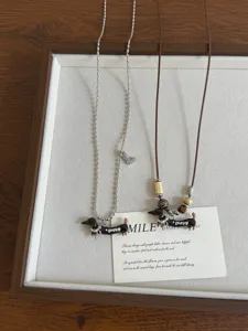 Detailed shot of retro oil drop dachshund pendant necklaces featuring metal chain and cord.