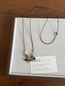 Retro oil-dropping dachshund necklace with adjustable brown cord and beaded design.