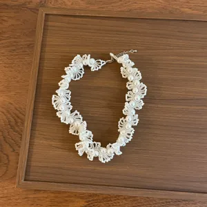 Détail de collier ras du cou en dentelle française et perles, design élégant pour femmes.