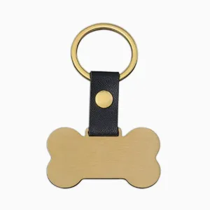 Vue de détail en gros plan d'une étiquette pour animal en métal doré avec lanière en cuir.