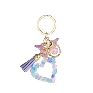 Vue rapprochée du porte-clés en résine avec pompon violet et pendentif papillon brillant.
