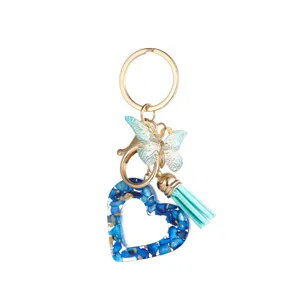 Gros plan détaillé du porte-clés en résine bleue avec papillon et pompon élégant.