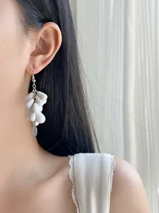 Primer plano detallado de elegantes pendientes colgantes de piedra irregular blanca.