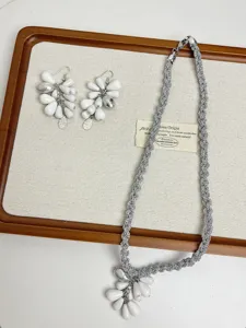 Conjunto de collar y pendientes trenzados a mano con elegantes cuentas blancas de lágrima.