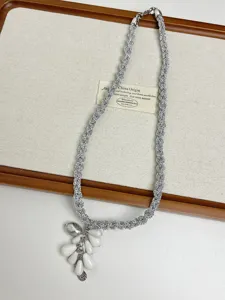 Collar trenzado plateado detalle con cuentas de lágrima blancas y textura artesanal.