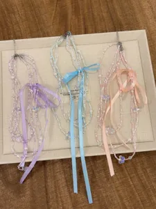 Primo piano di collane di perle a strati con fiocchi nei delicati toni rosa, blu e viola.